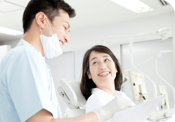 男性歯科医が診察台に座っている患者と笑顔で話している写真