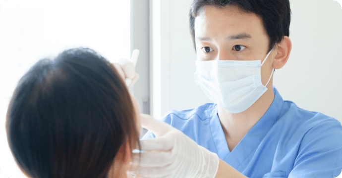 男性歯科医が患者の口の中を診ている様子